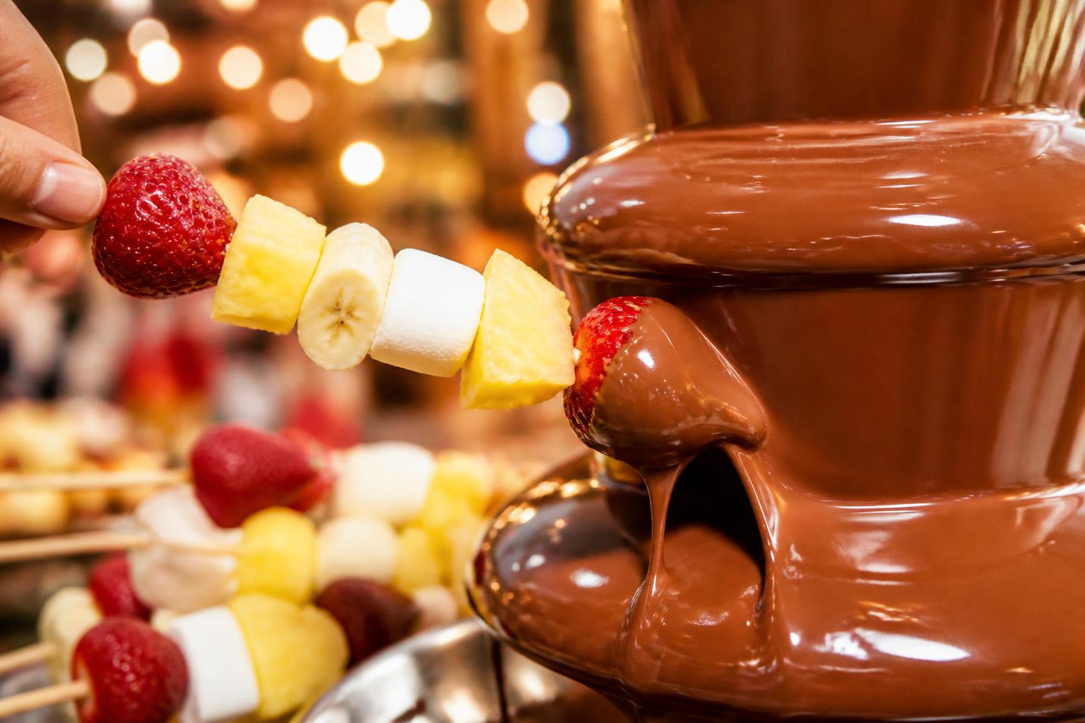 Fruit skewer being dipped in chocolate